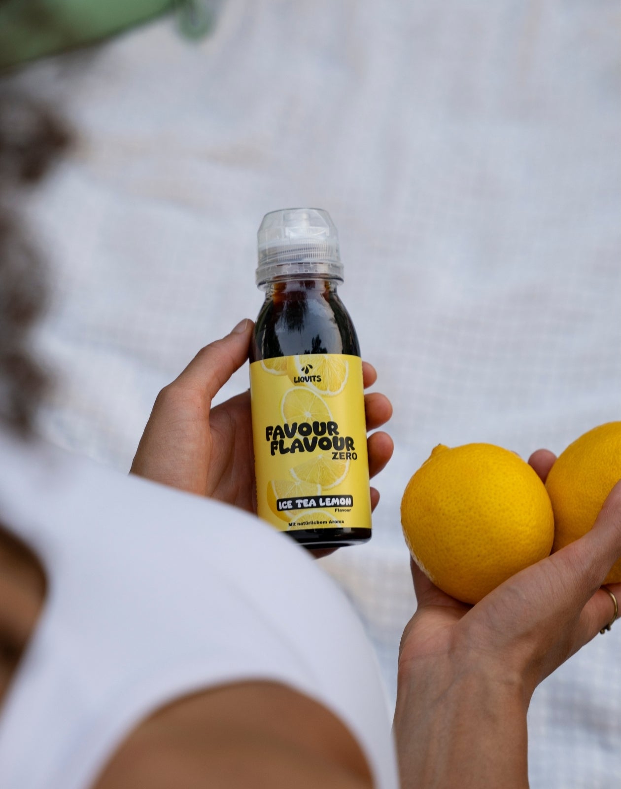 LiqVits FavourFlavour Sirup Konzentrat zuckerfrei Natürliches Aroma Ice Tea Leom Lifestyle Bild mit Model das 2 Zitronen in der Hand hält