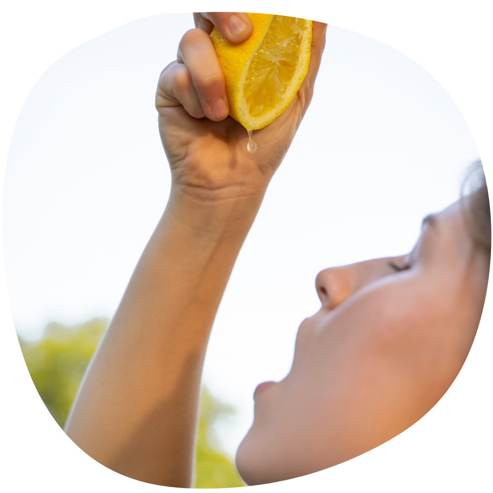 Stockphoto Lifestyle Outdoor mit einer Frau die eine Zitrone direkt in ihren Mund auspresst